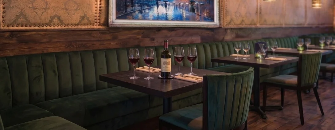Elegant restaurant interior with green velvet seating and wine bottles