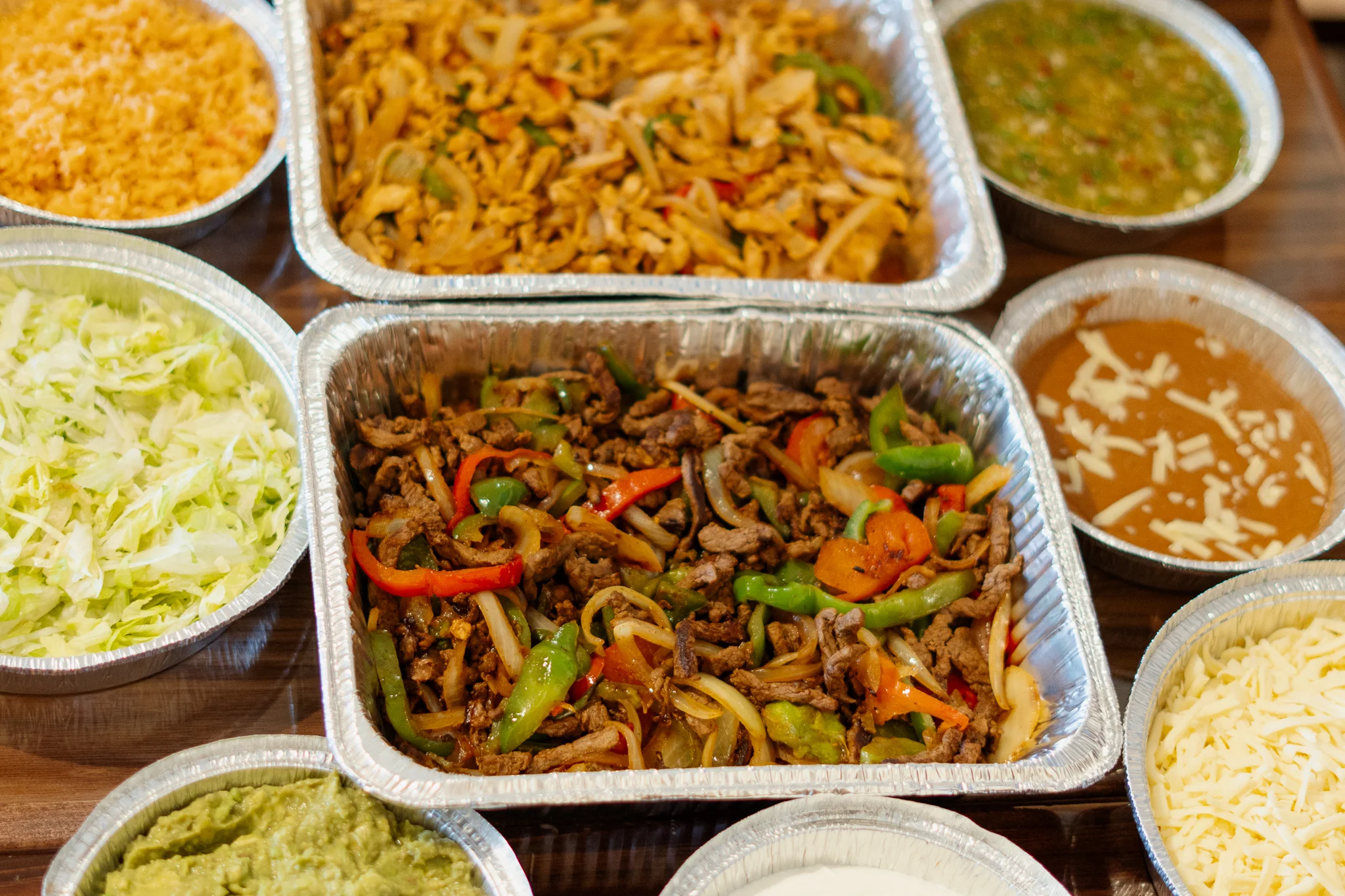 Sizzling fajitas served in a foil tray with fresh toppings