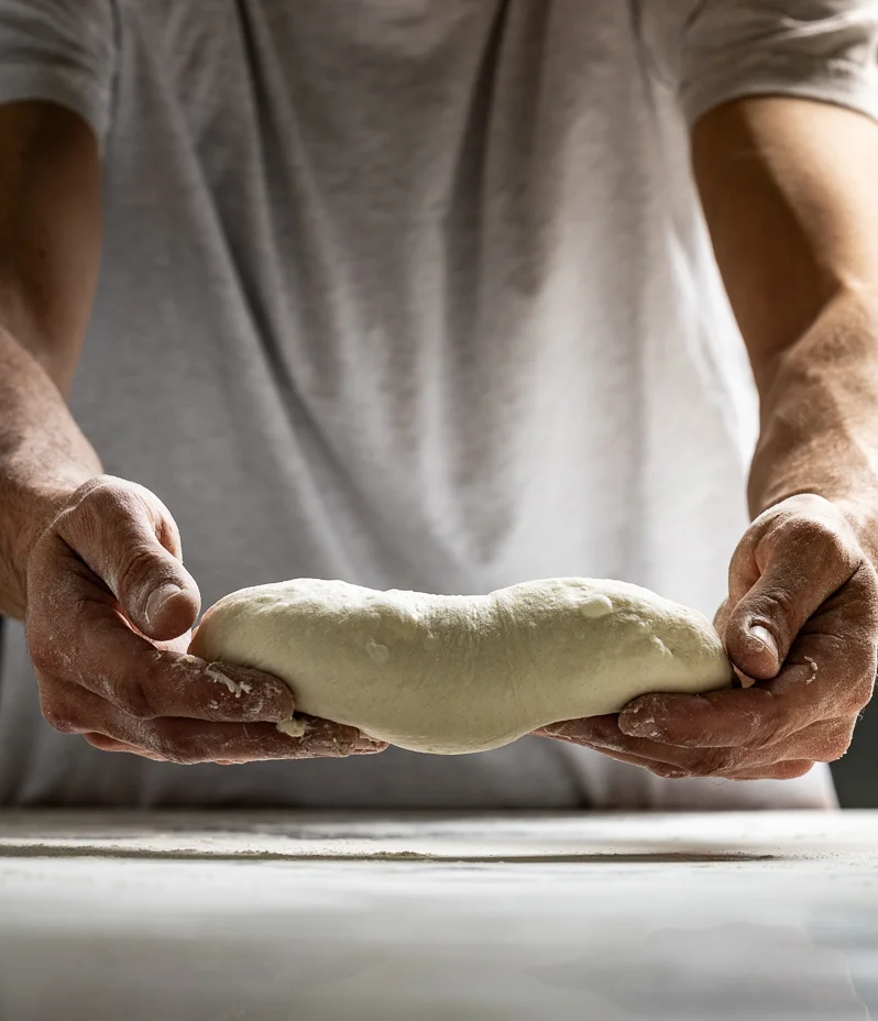 Baker at La Boulangerie & Co in Chicago presenting proofed bread dough, showcasing artisanal results.