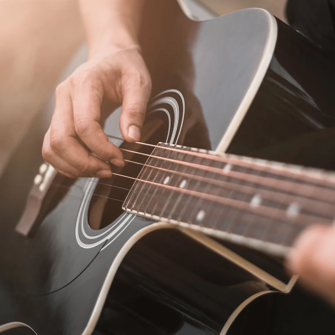Close-up of a hand strumming an acoustic guitar