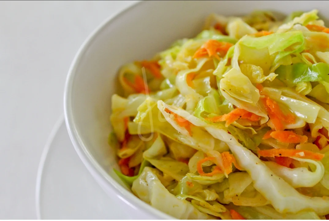 A bowl filled with a colorful mix of shredded cabbage and carrots, highlighting the freshness of the vegetables.