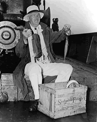 Fisherman holding a catch on a vintage boat
