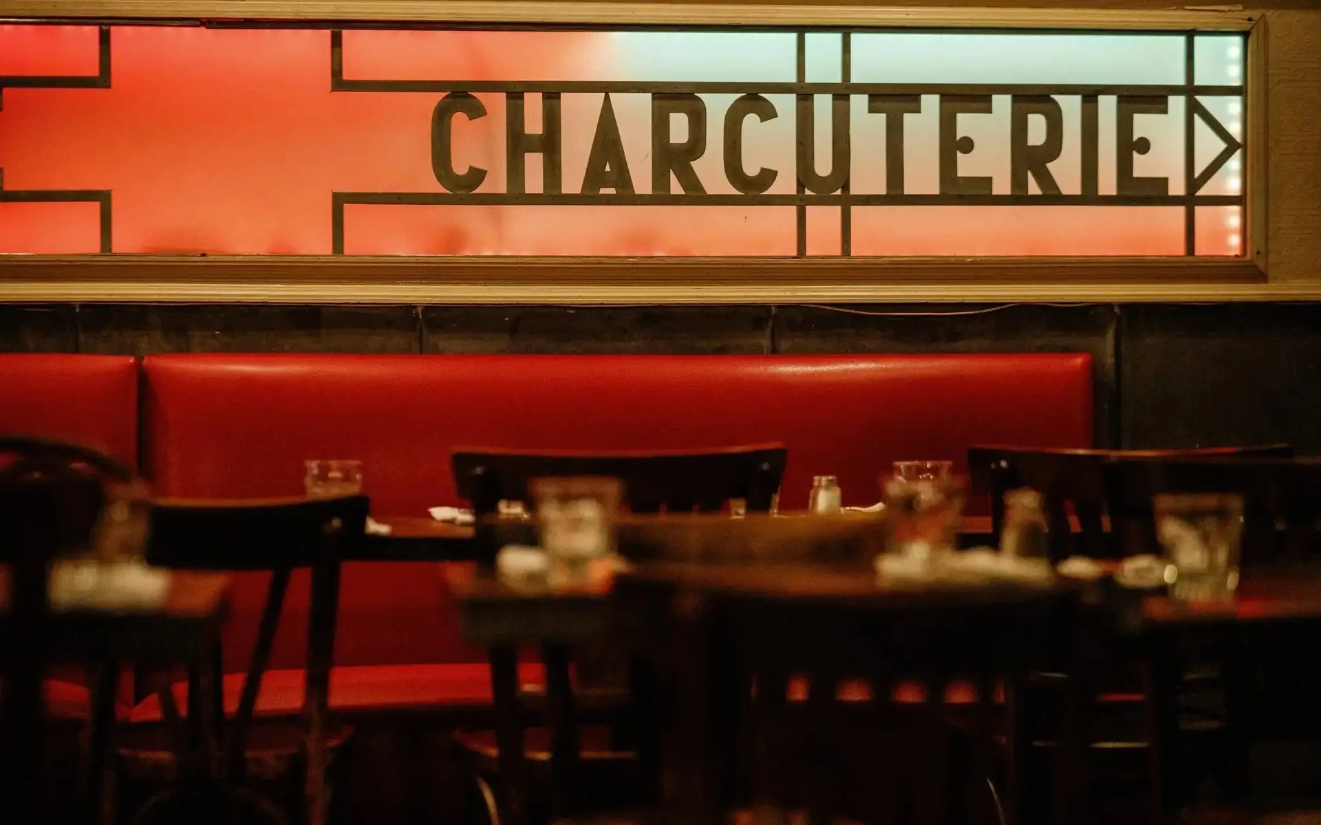 Cozy restaurant interior featuring charcuterie sign and red seating