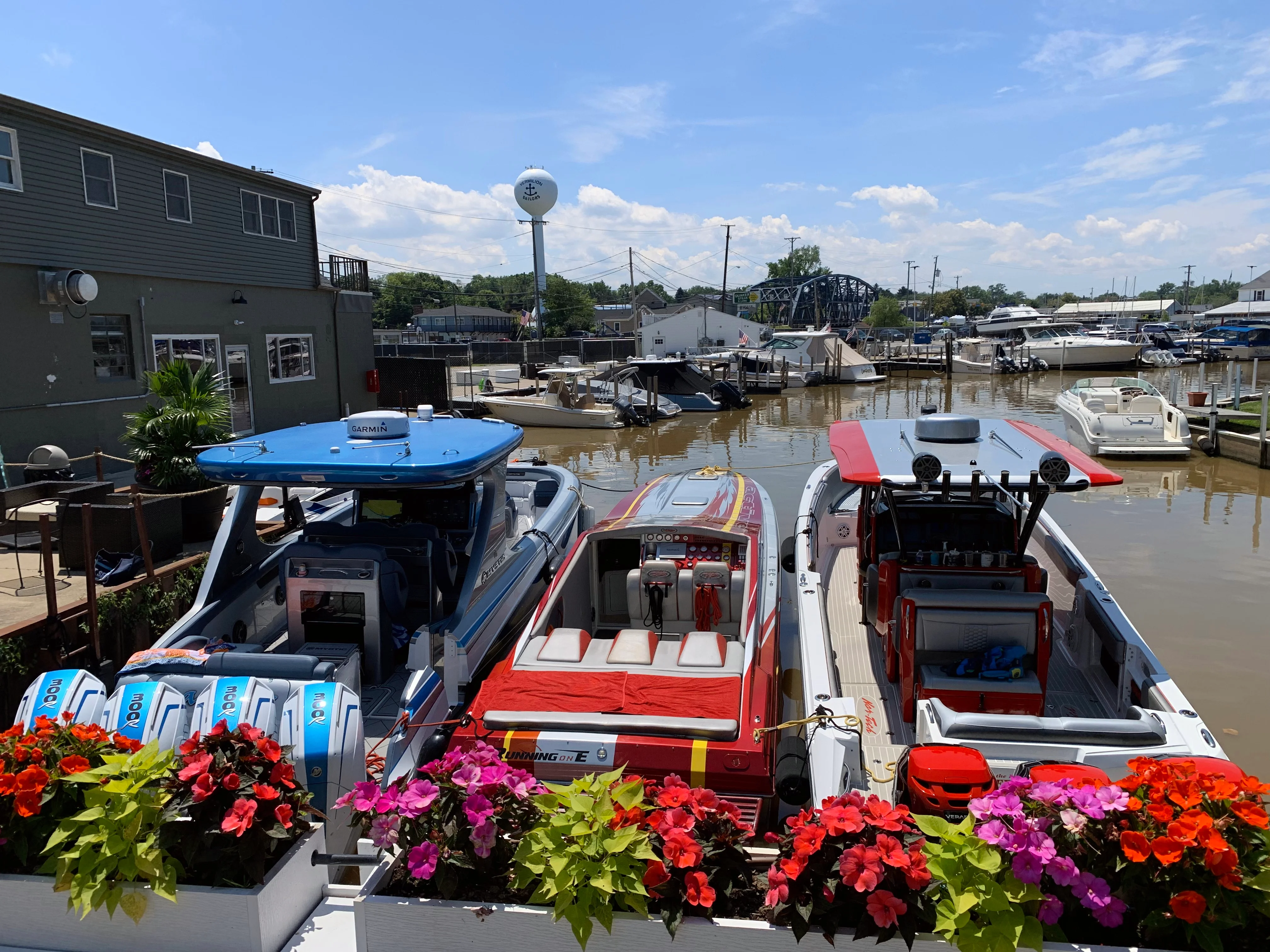 Colorful boats docked at a marina with vibrant flowers in the foreground