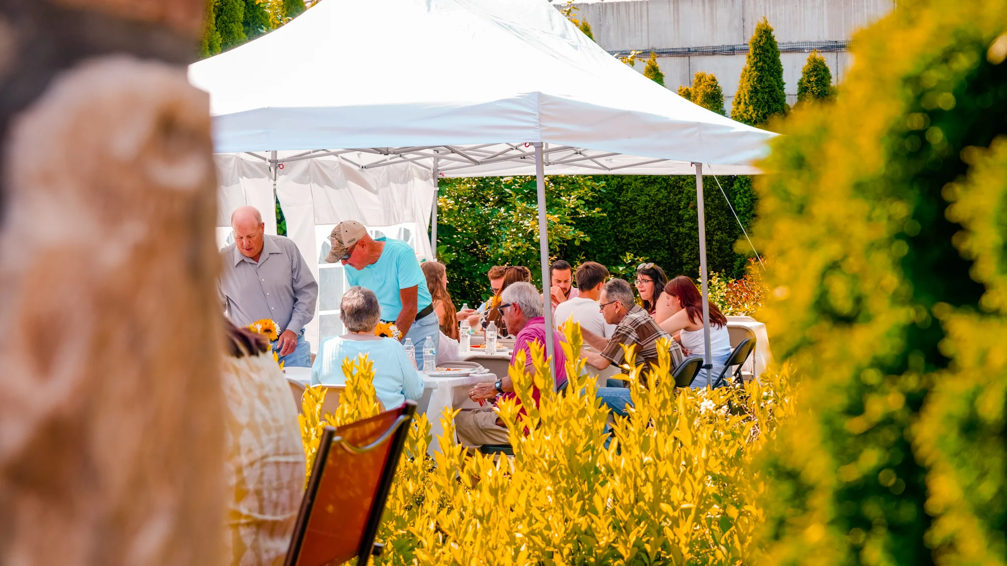 Outdoor dining event under a tent with guests enjoying a meal