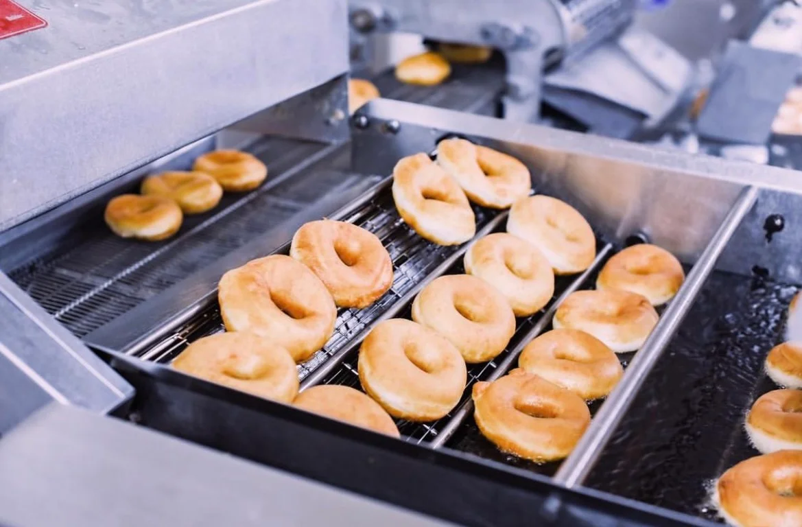 Freshly fried donuts on a conveyor belt