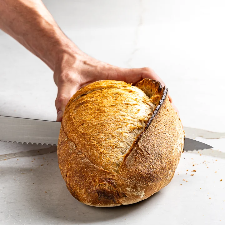 Chef slicing La Boulangerie & Co sourdough loaf for service at a partner restaurant
