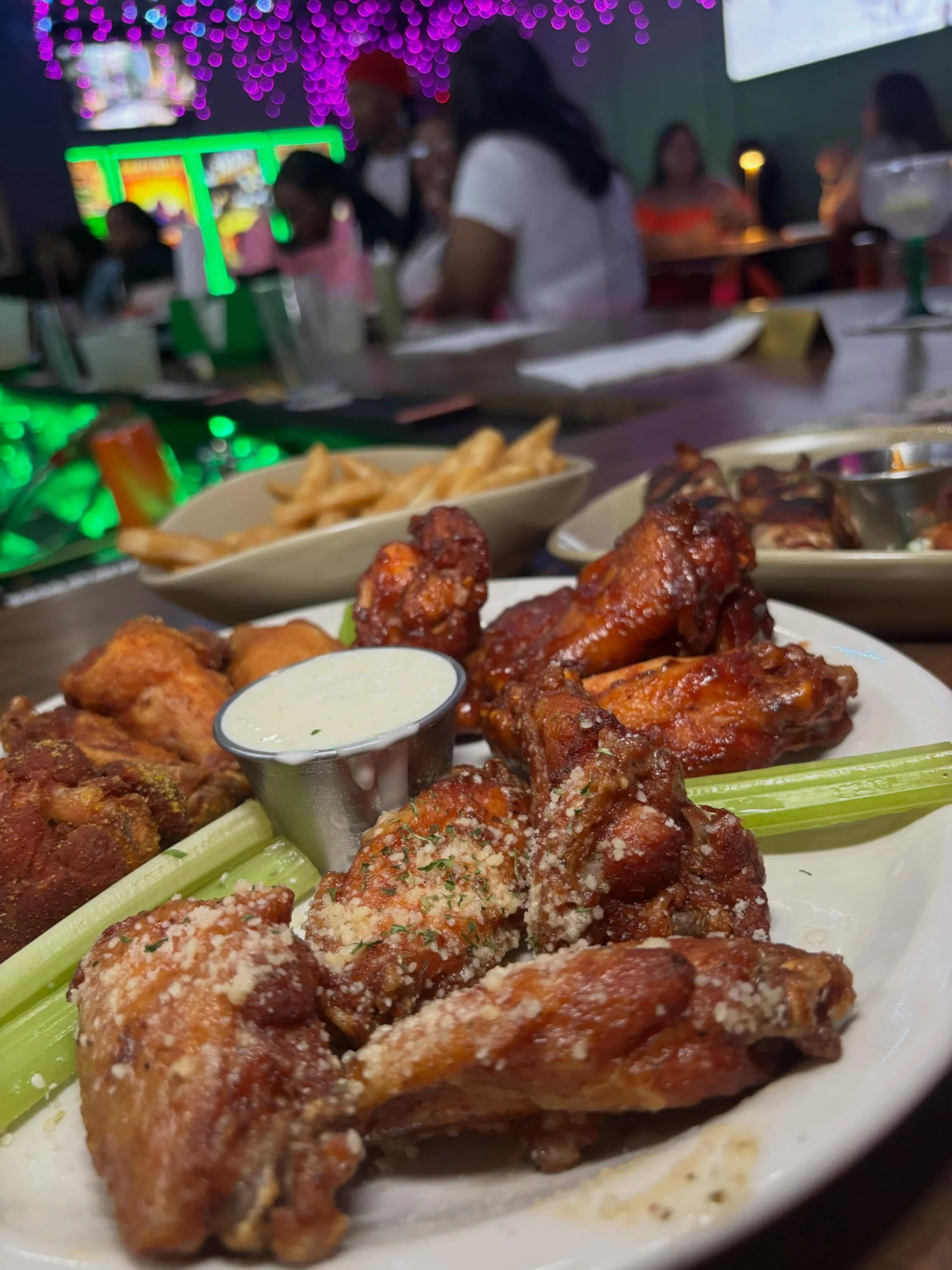 A plate of crispy chicken wings accompanied by a side of ranch dressing and celery sticks.