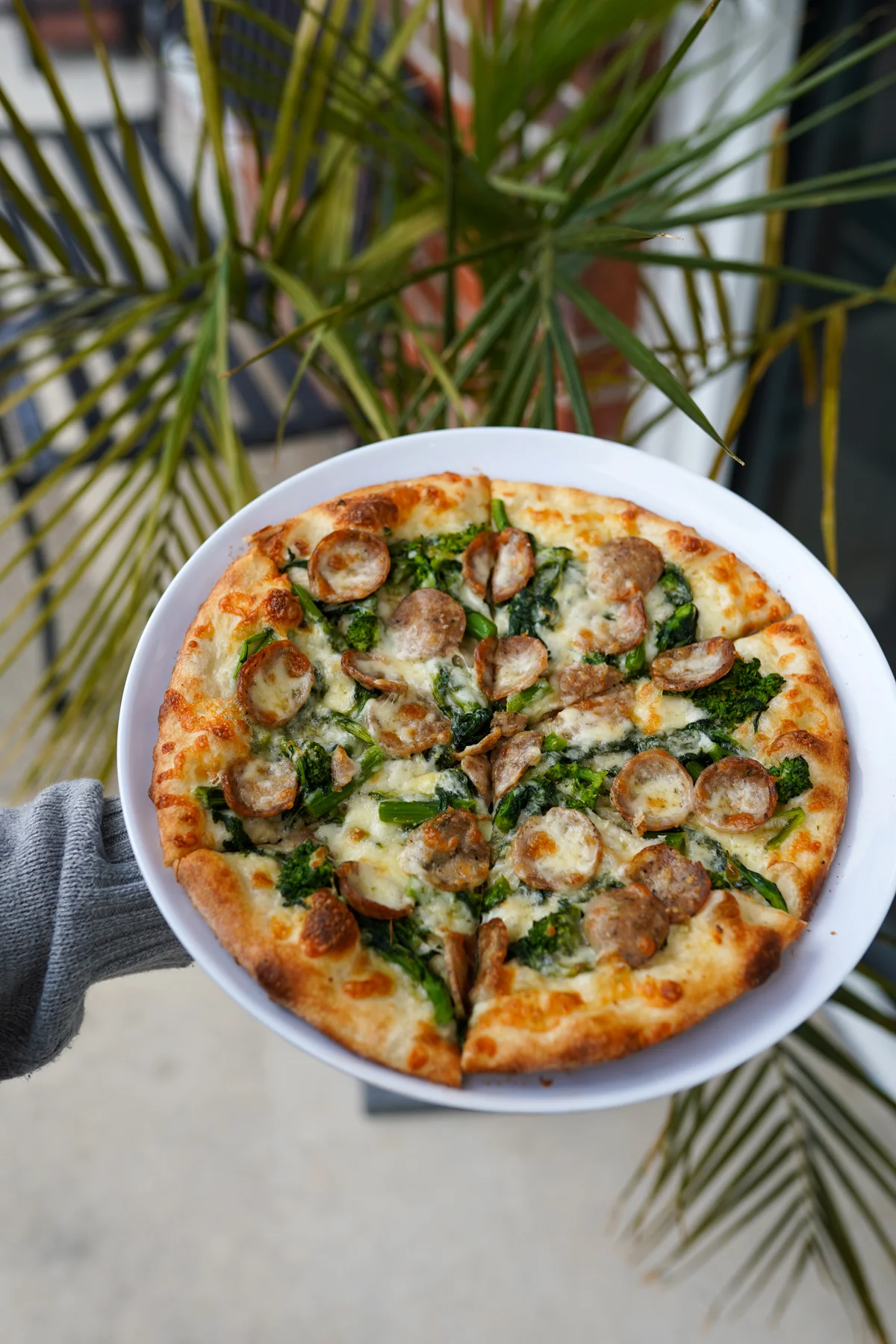 Italian sausage and broccoli rabe pizza on a white plate