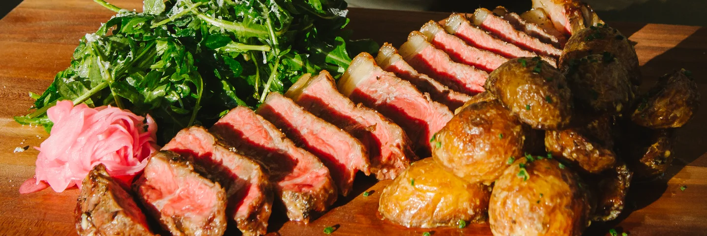 Sliced steak with arugula salad and roasted potatoes