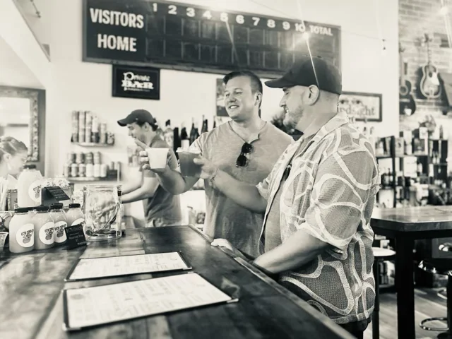 Two friends toasting drinks at a lively bar
