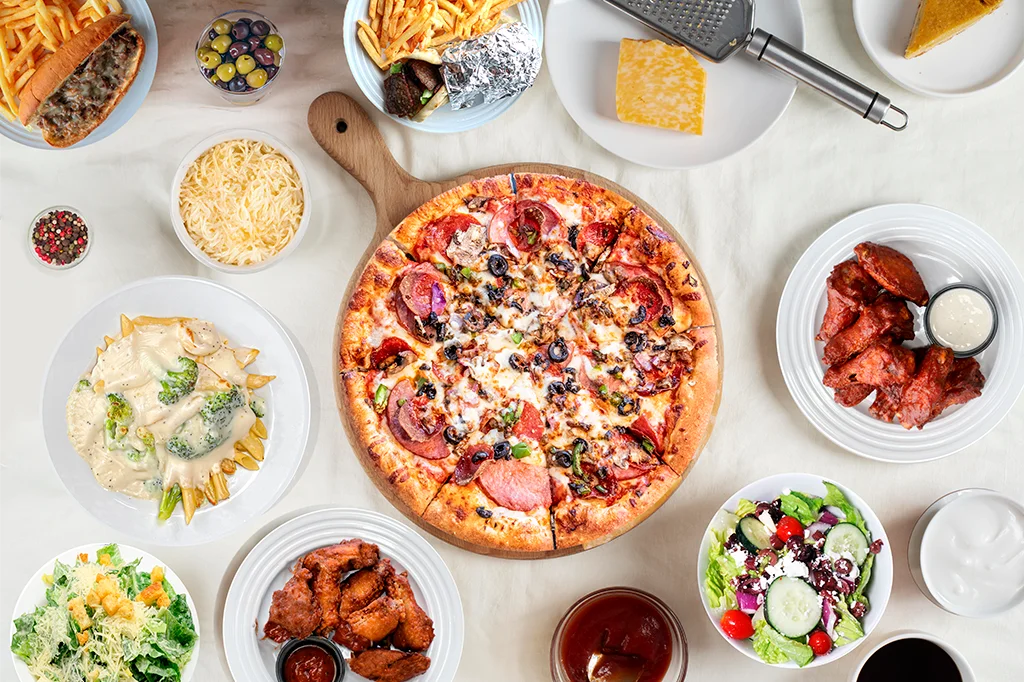 Delicious pepperoni pizza with sides of wings and pasta in a casual dining setting