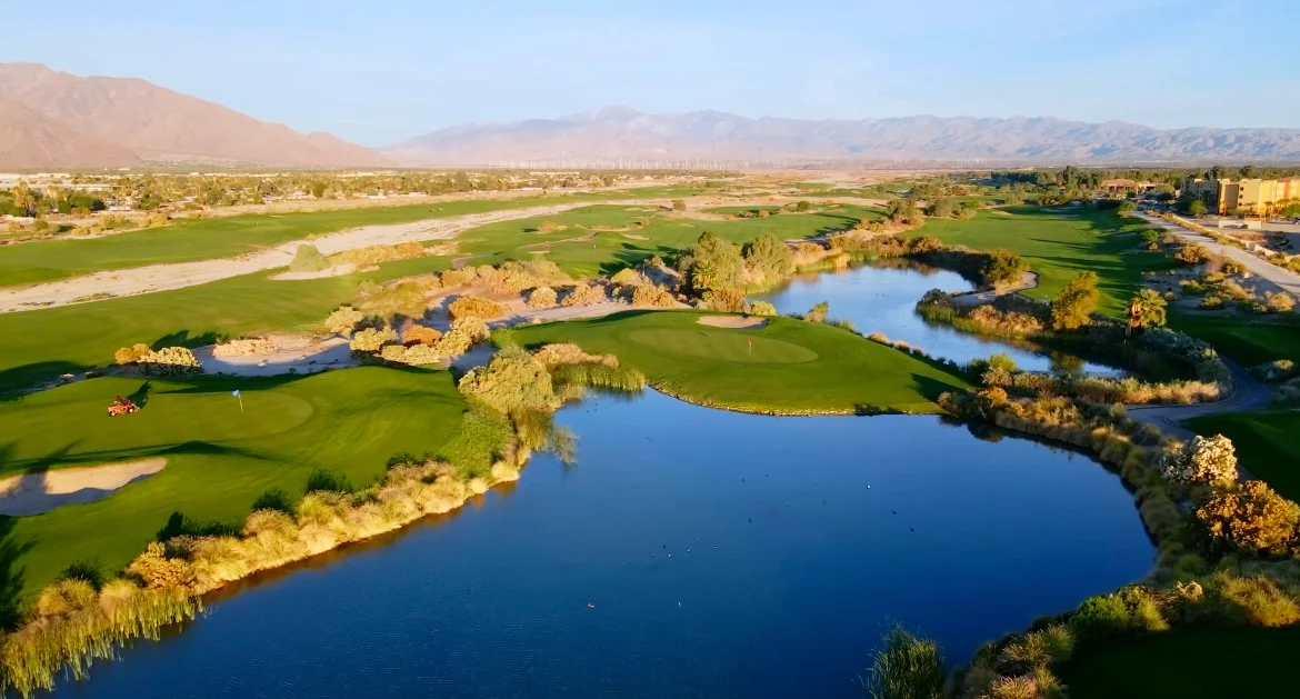 Aerial view of a scenic golf course with lakes and mountains