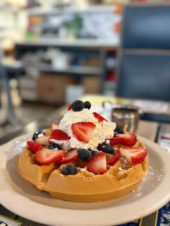 Fluffy Belgian waffle topped with berries and whipped cream