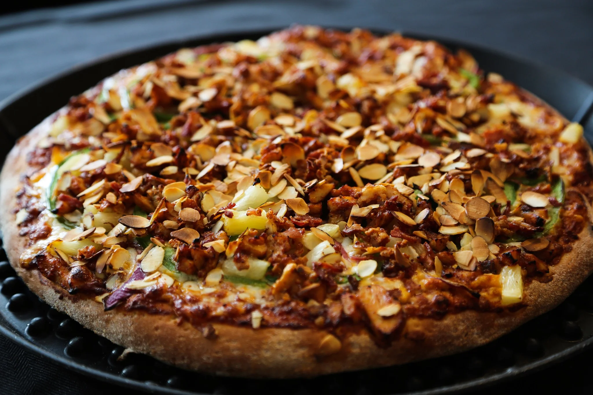 Gourmet pizza topped with almonds and savory ingredients
