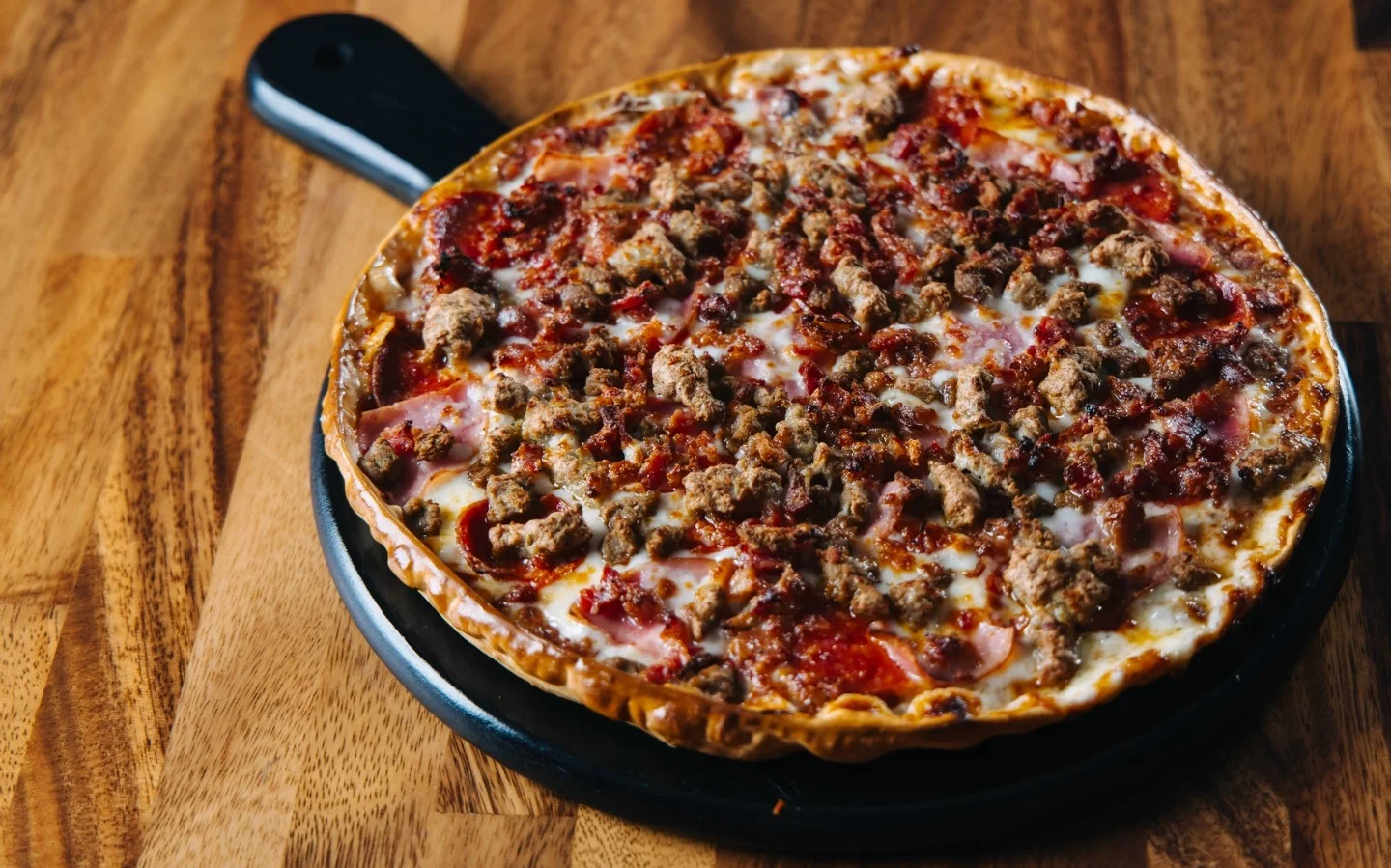 Loaded meat lover's pizza on a wooden serving board