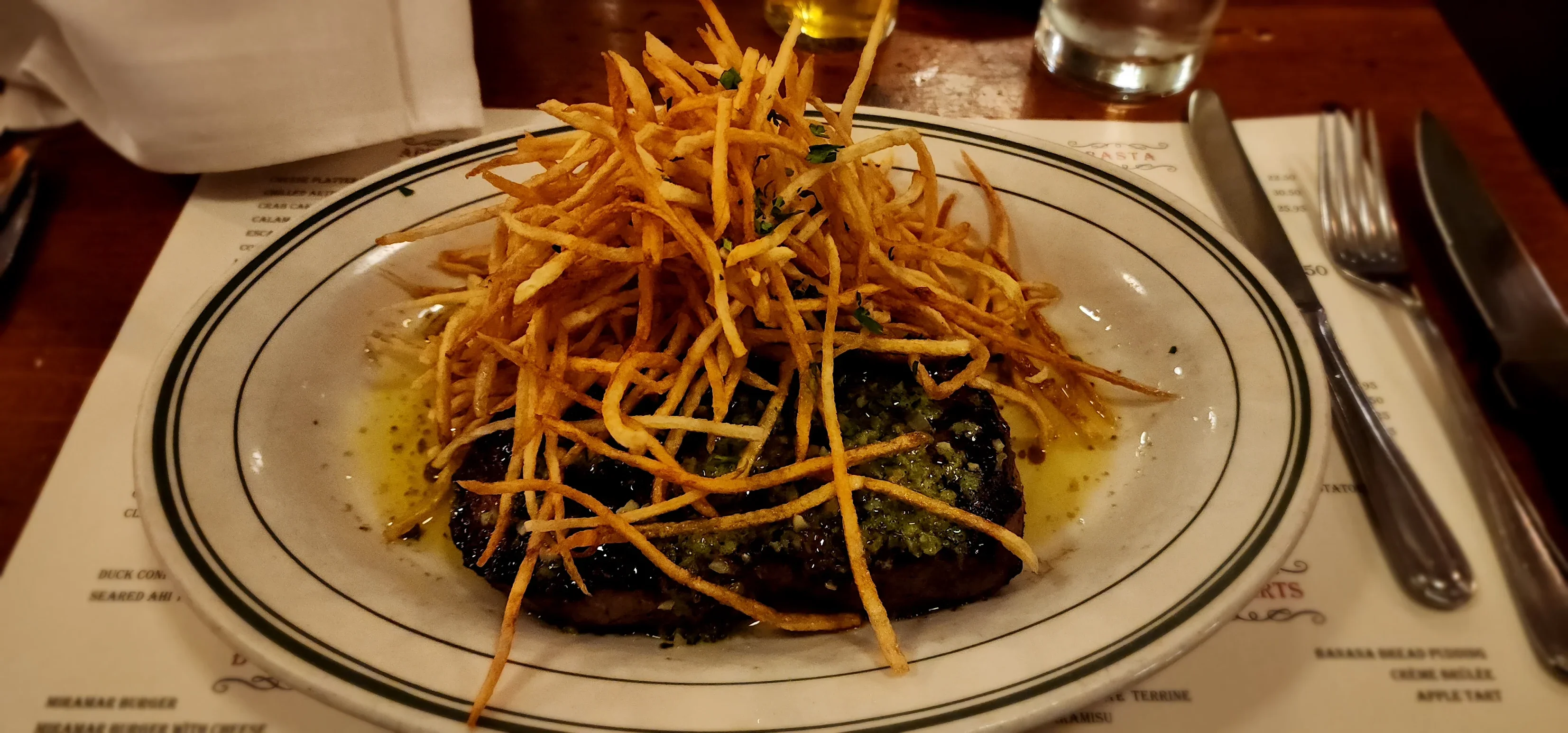 Grilled steak topped with crispy shoestring fries, a classic American dish