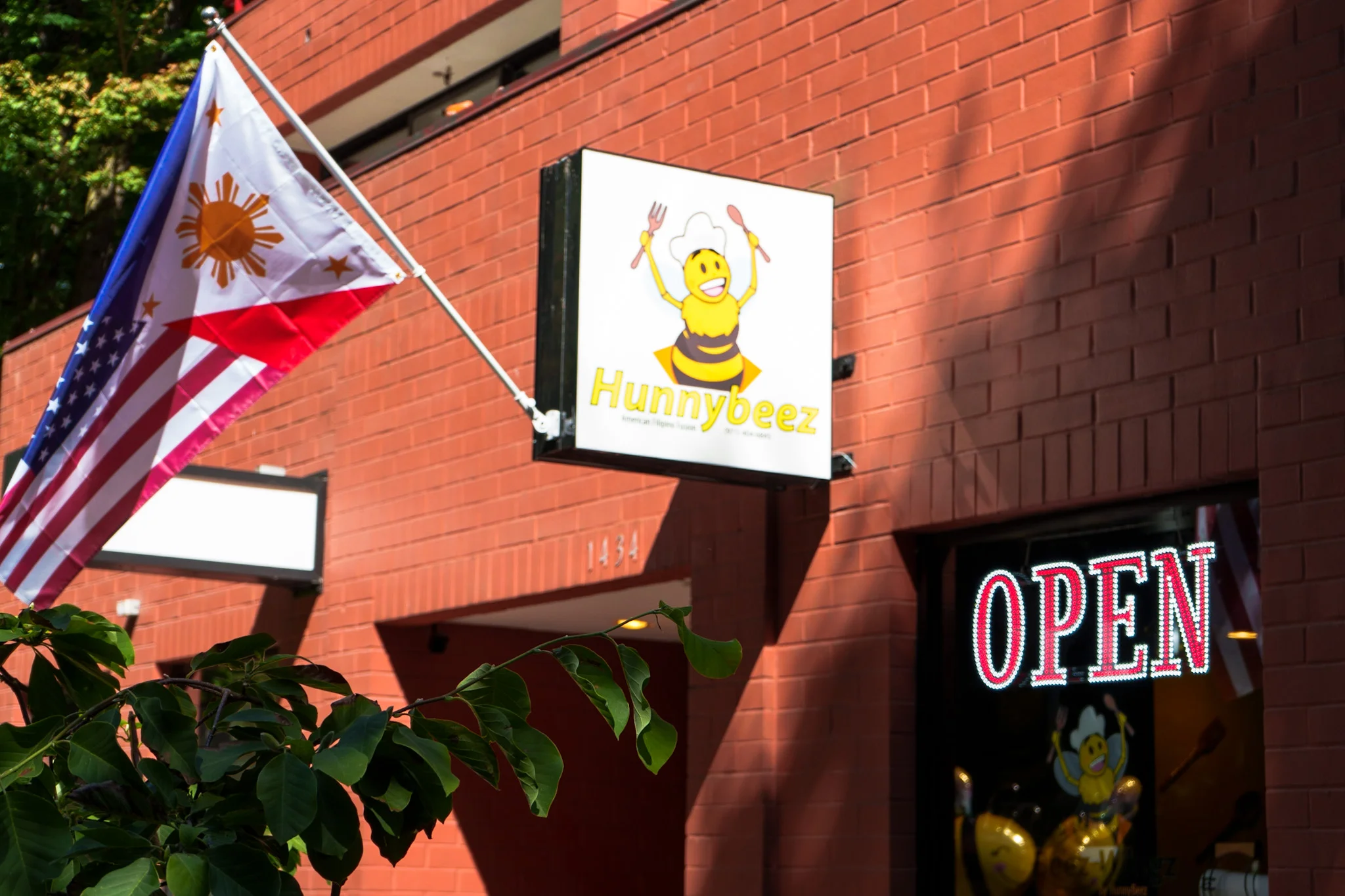 Exterior of Hunnybeez restaurant with flags and open sign