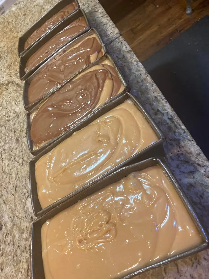 Several baking pans filled with different layers of creamy batter, showcasing various shades of brown.