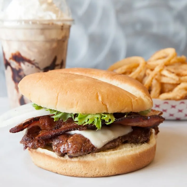 Cheeseburger with bacon. Shake and fries in the background.