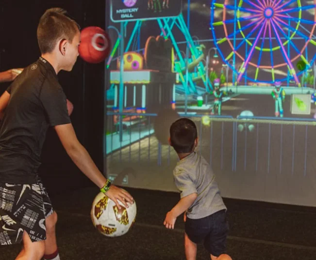 Children playing interactive games with a colorful carnival backdrop