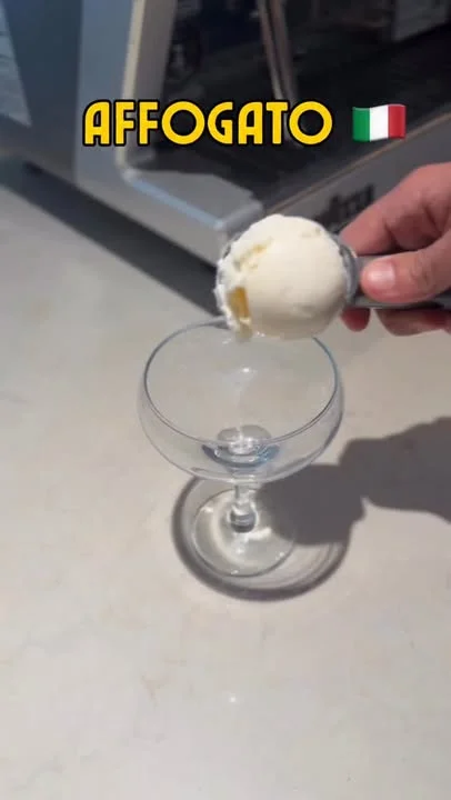 A scoop of ice cream being placed into a glass, preparing for an affogato dessert.