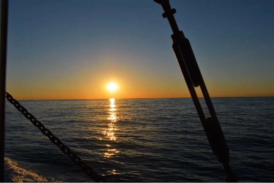 A breathtaking sunset over calm waters, with sunlight reflecting on the surface.