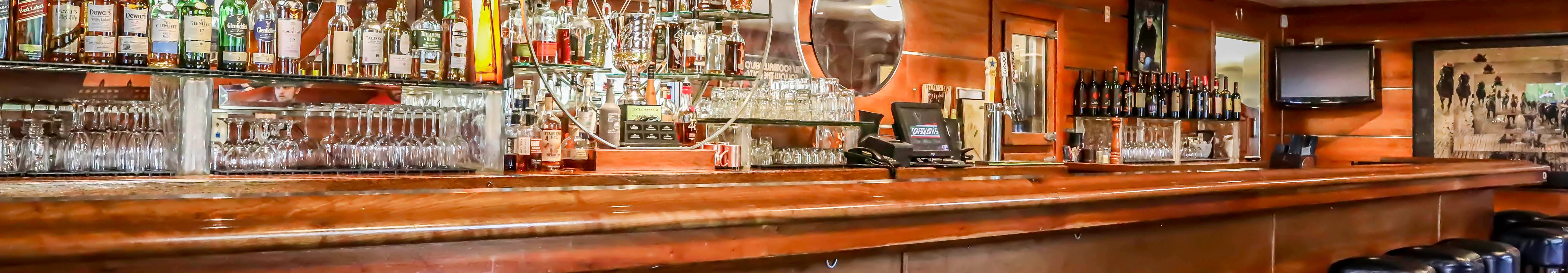 Well-stocked bar counter with various spirits and glassware