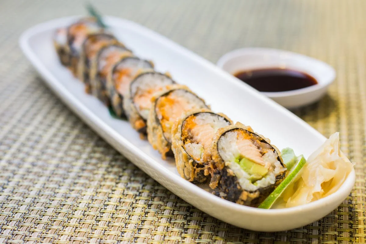 Plate of sushi rolls with dipping sauce and garnishes