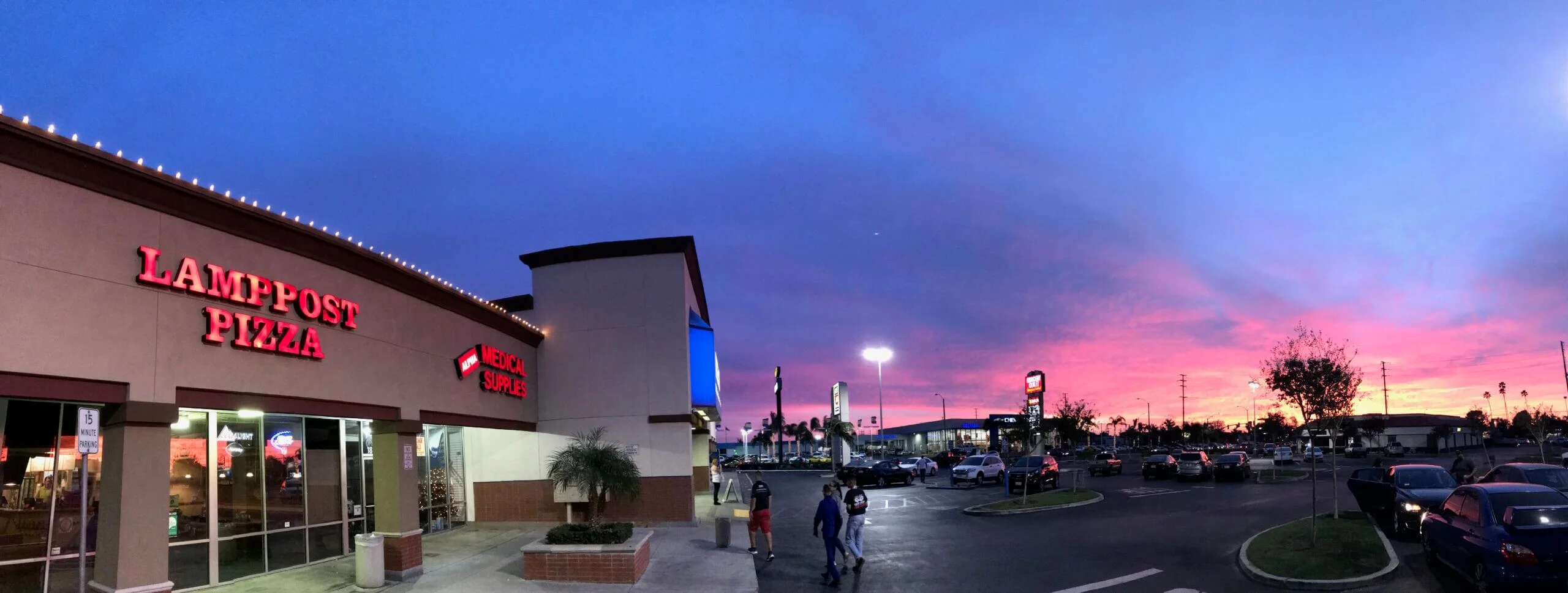 Lamppost Pizza storefront at sunset with vibrant sky colors.