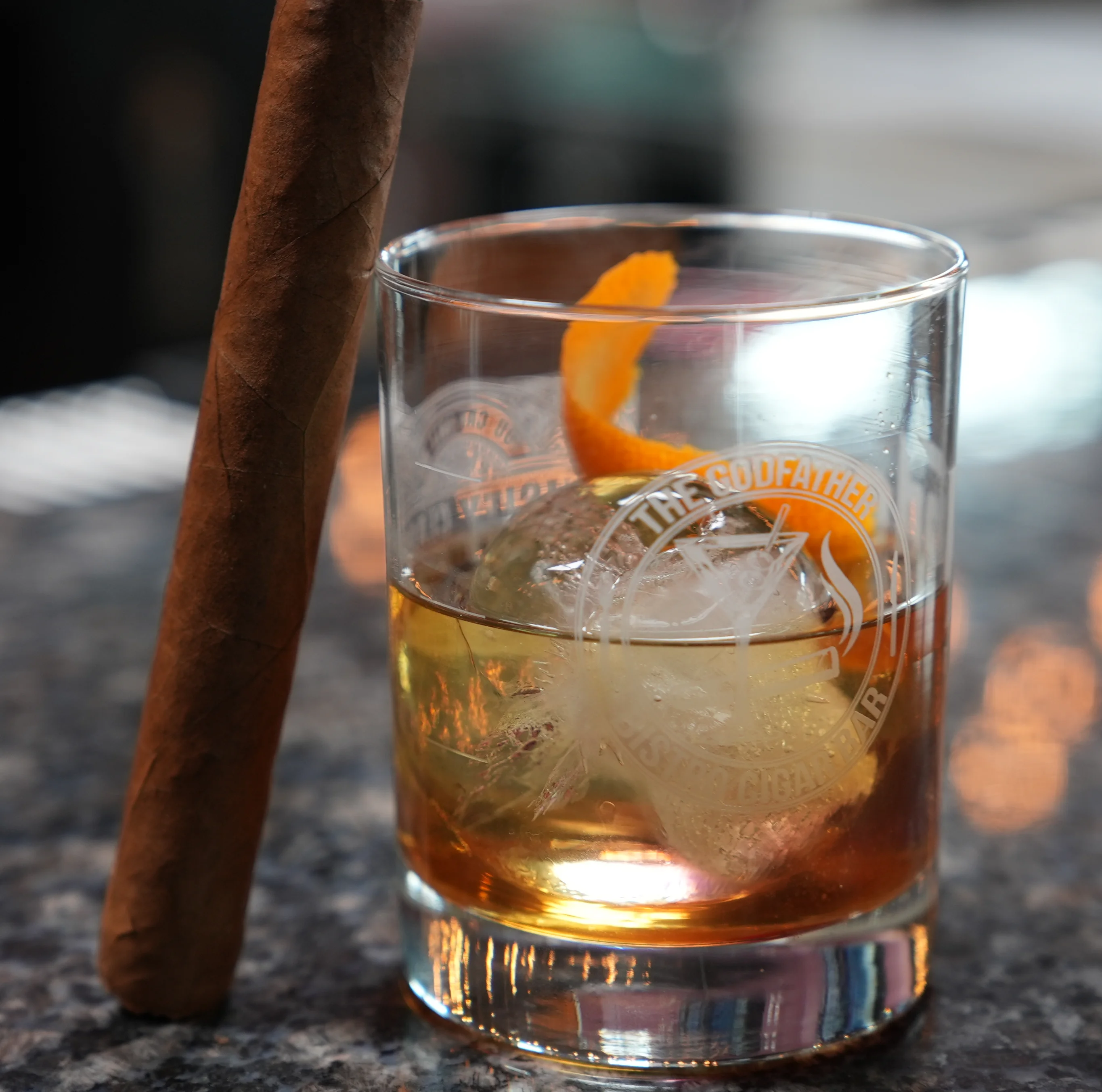 A classic old-fashioned cocktail with a cigar on a wooden table.