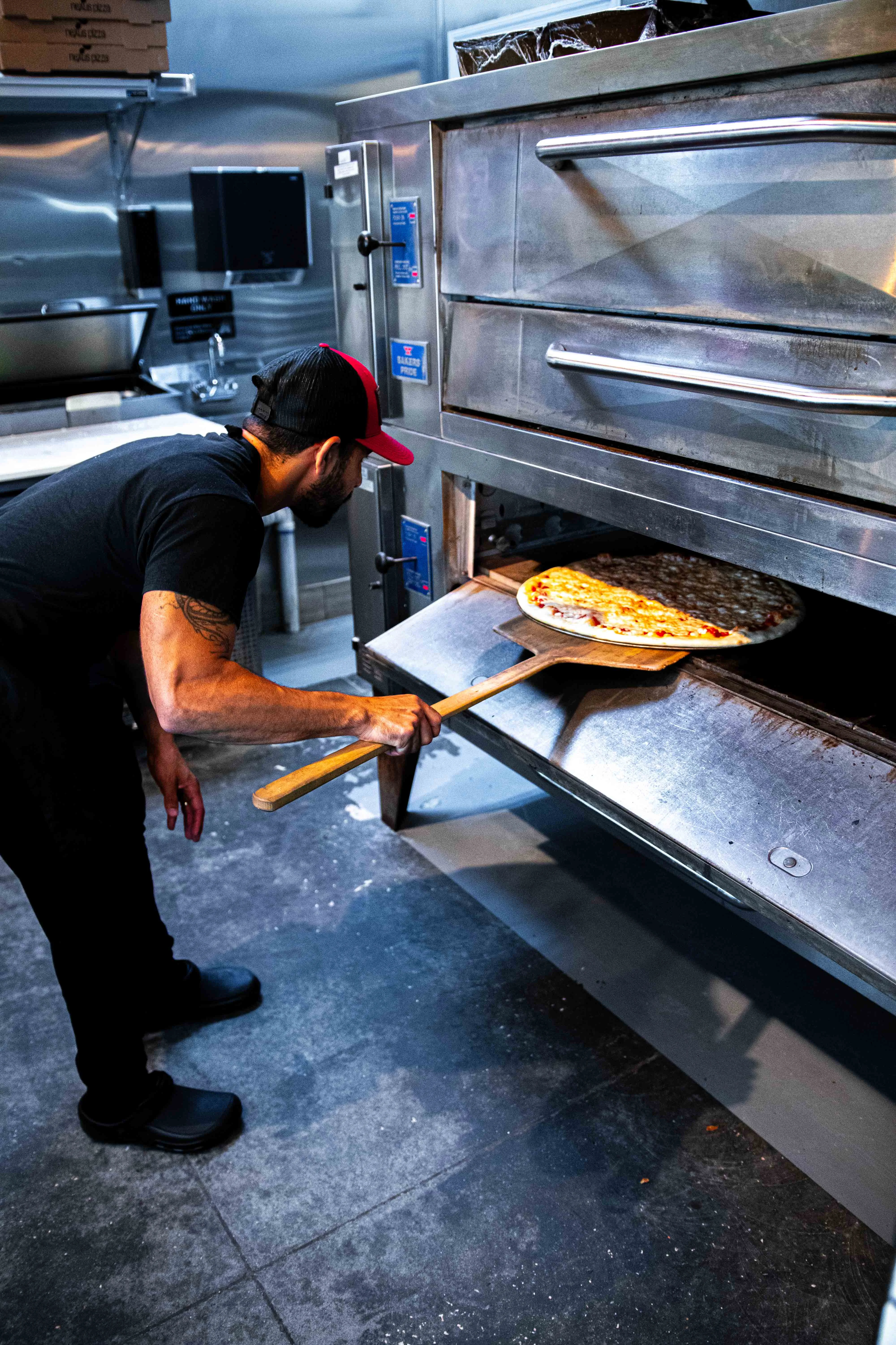 Chef retrieving a Margherita pizza from a commercial oven