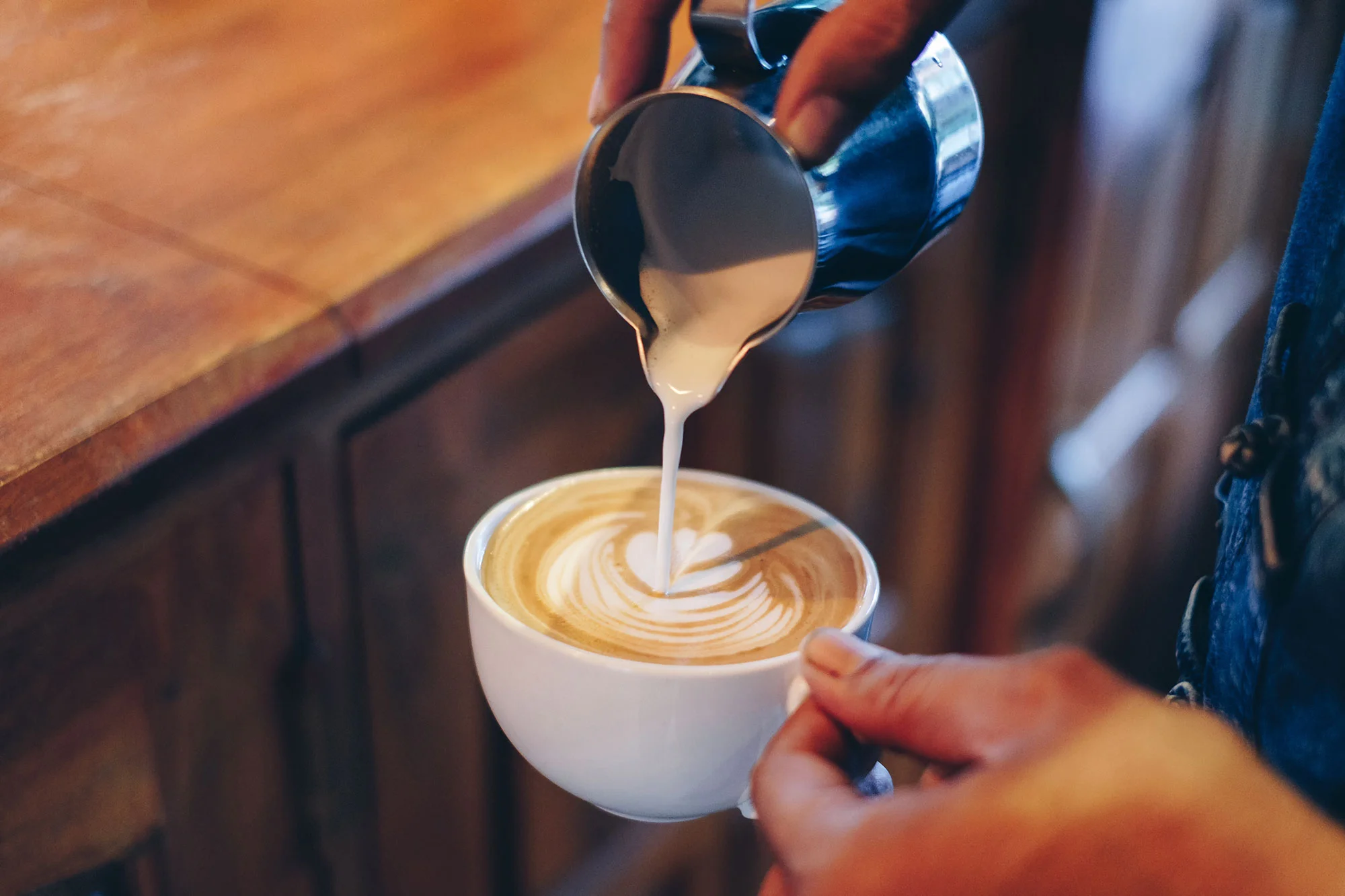 Barista pouring latte art into a cup of coffee