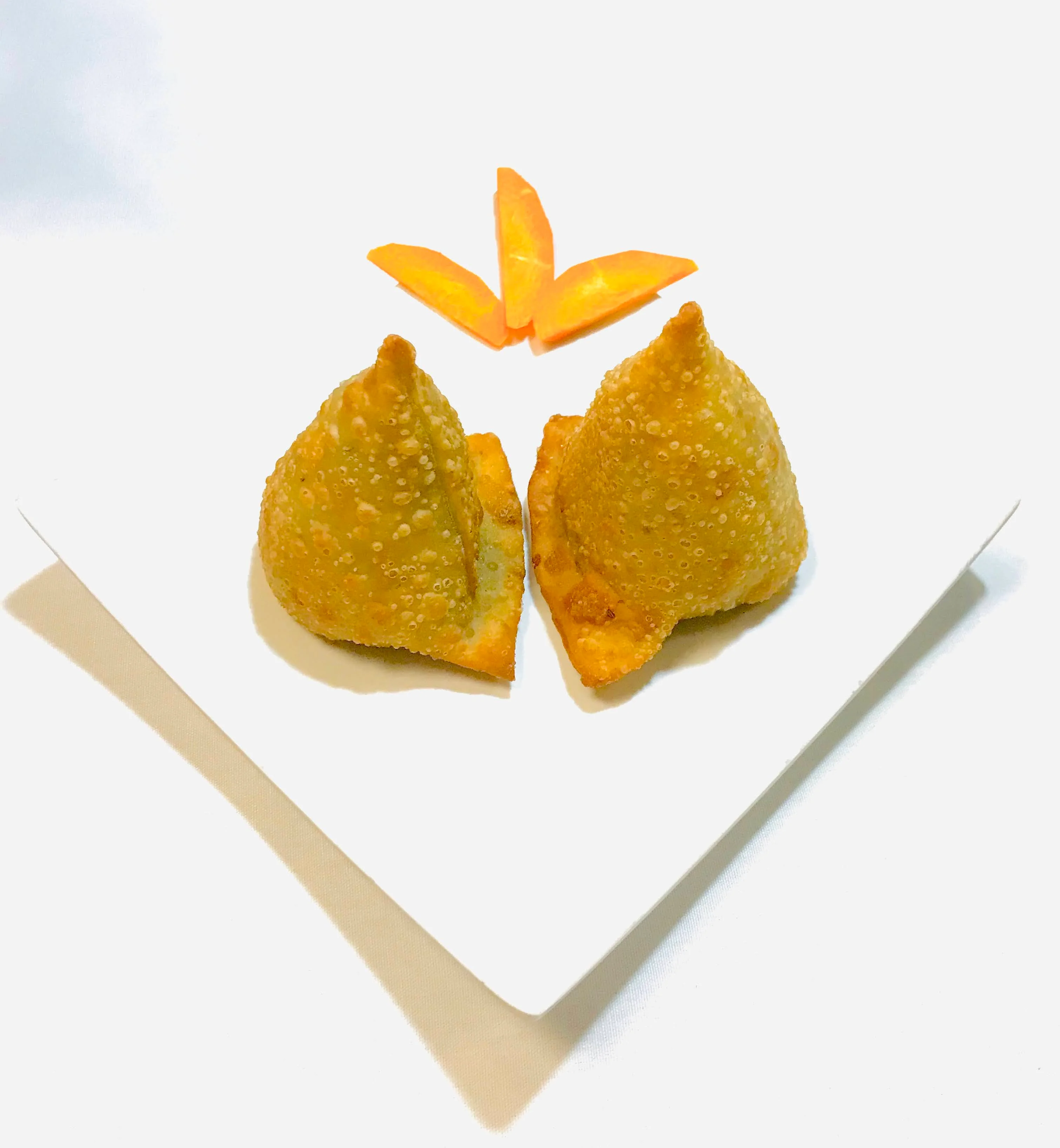Crispy Indian samosas served with carrot garnish