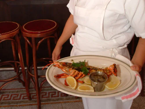 Grilled lobster served with lemon and sauce in a restaurant setting