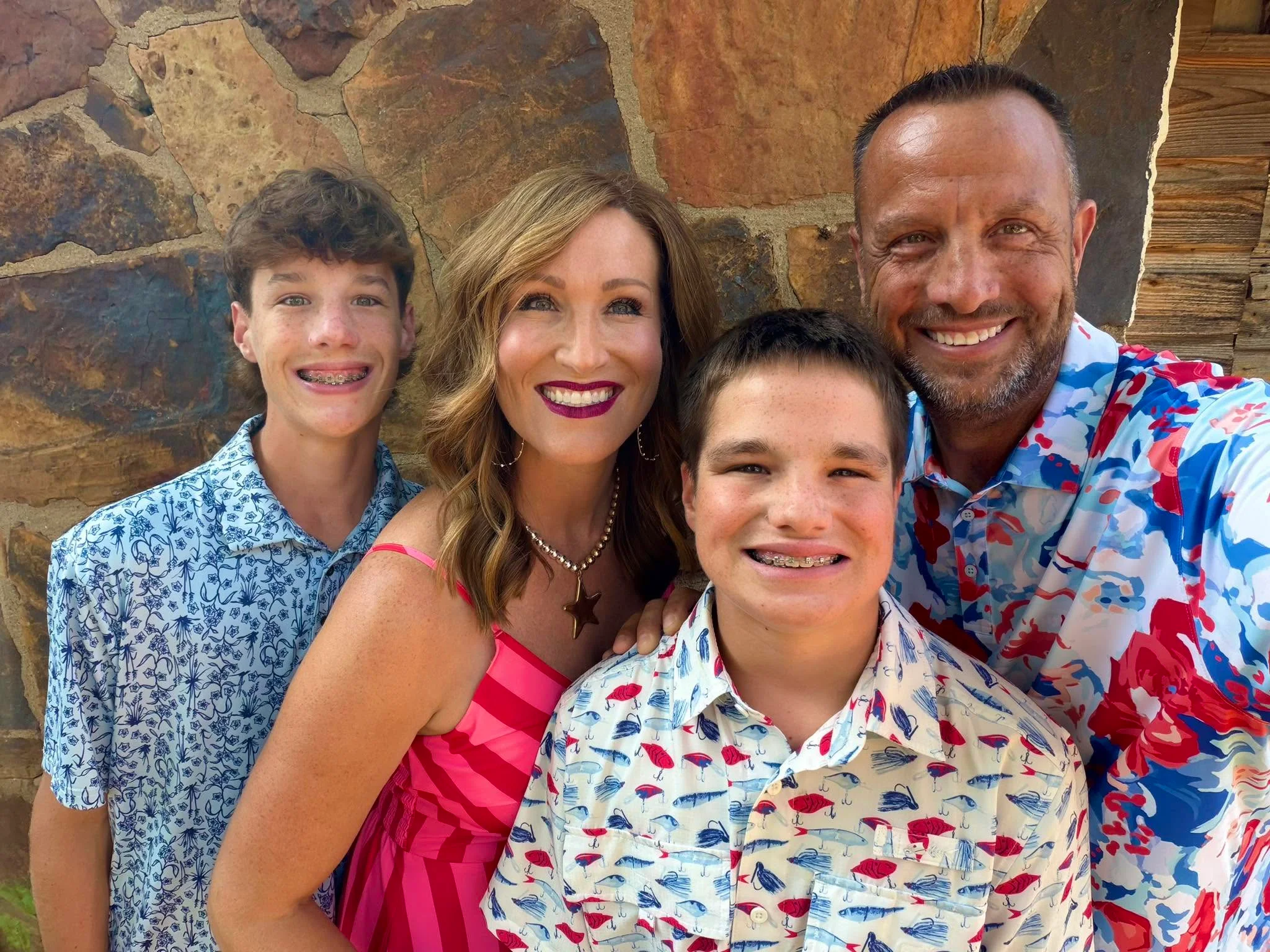 Family portrait with vibrant summer outfits against a stone wall backdrop