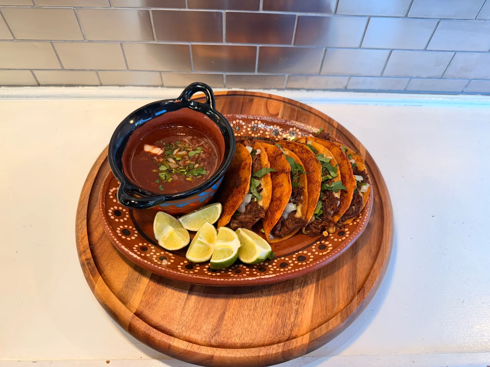 Authentic Mexican tacos with consomé and lime wedges