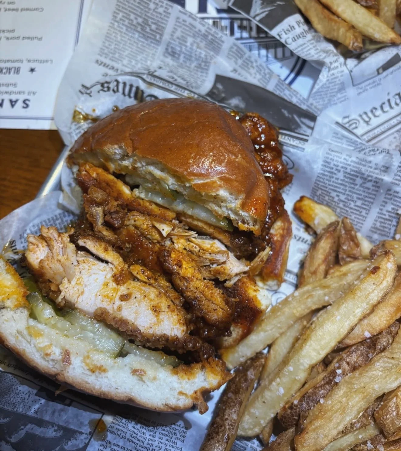 A delicious chicken sandwich stacked with crispy fried chicken and pickles, served with a side of golden fries.