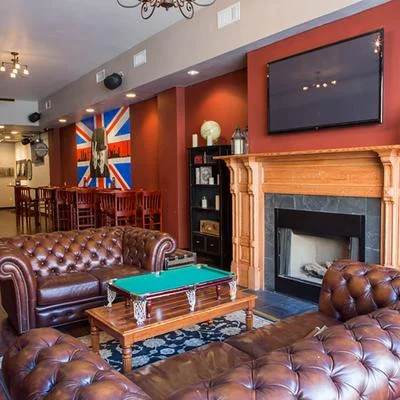 A cozy lounge area in a bar with large leather sofas, a coffee table, and a fireplace, showcasing a rustic design.