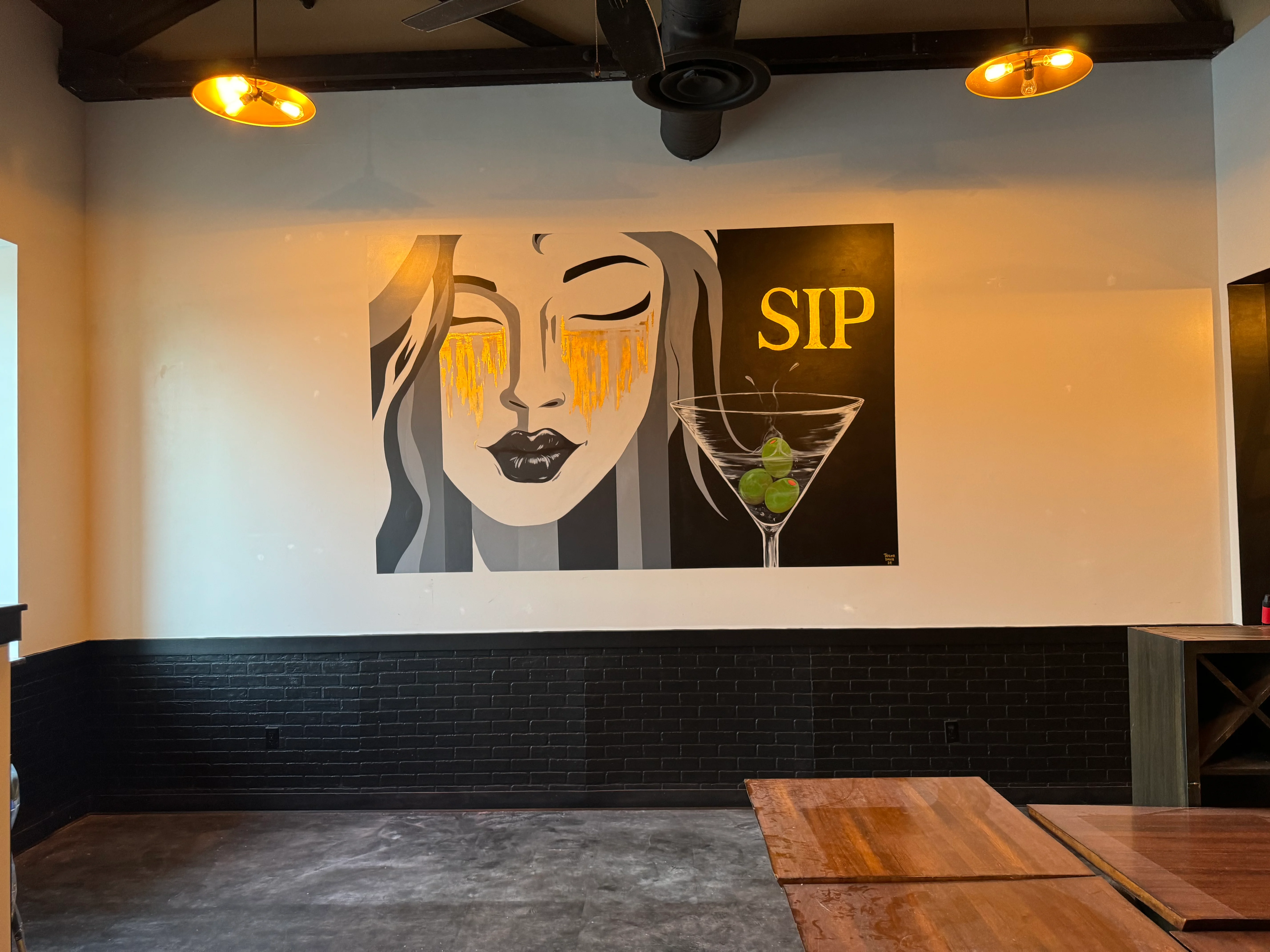 Artistic mural featuring a cocktail and the word 'SIP' in a modern bar setting