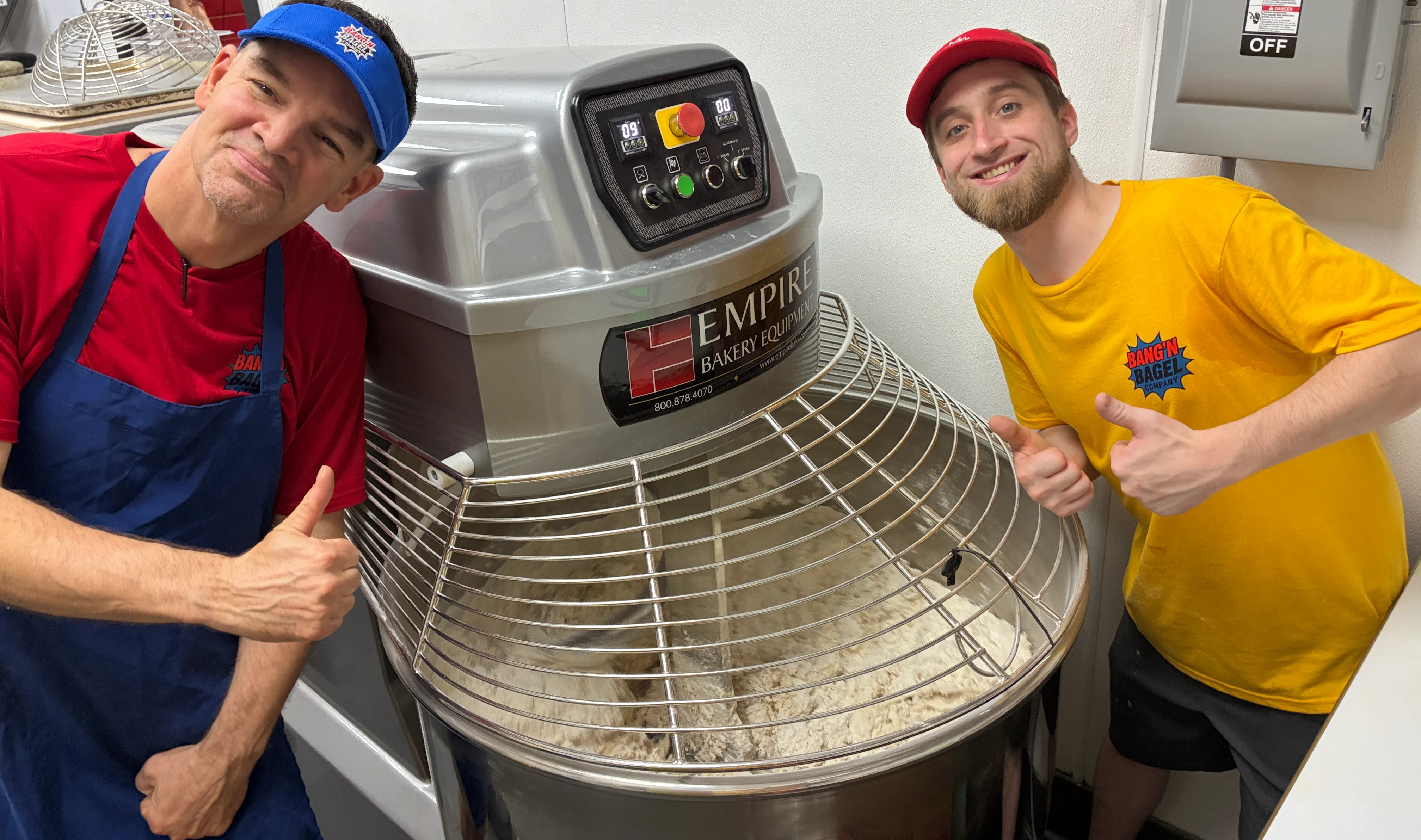 Bakers posing with a large dough mixer in a bakery
