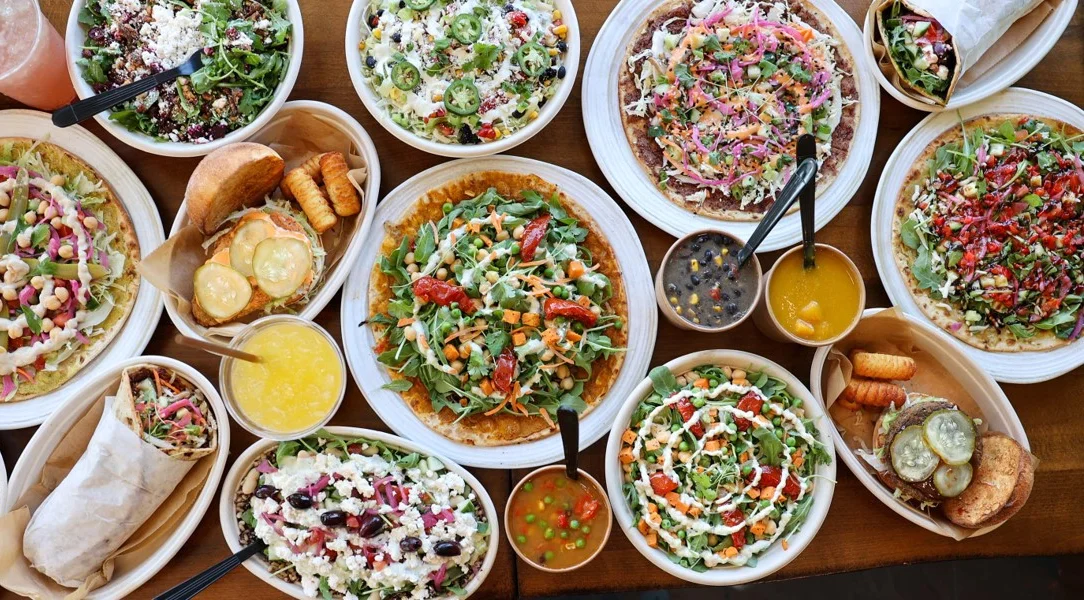 table spread of worldFLATS menu items such as flats, soups, salads, bowls, sandwiches and drinks