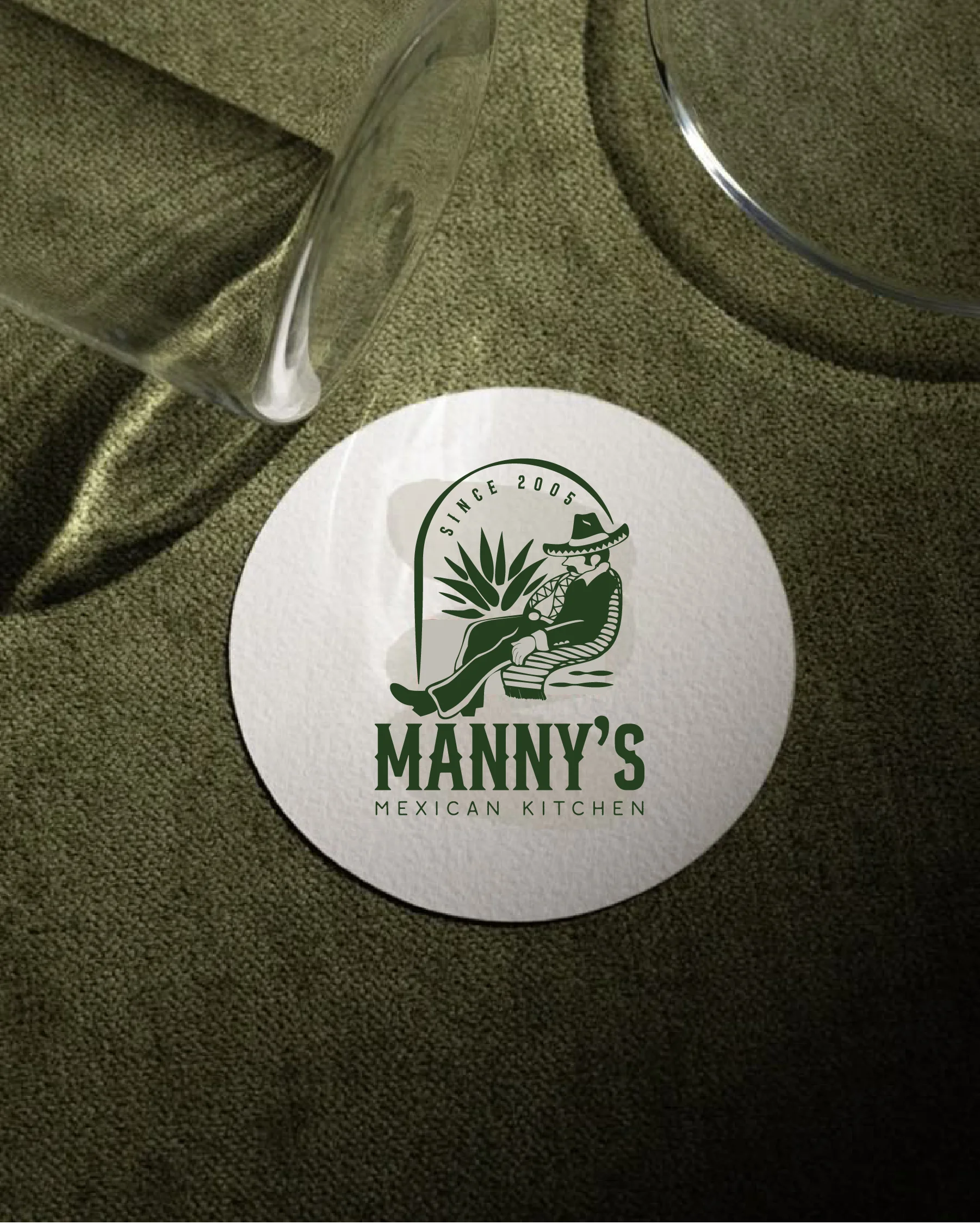 A graphical logo featuring the text 'MANNY'S MEXICAN KITCHEN' with an illustration of a seated figure wearing a hat, alongside a plant design. The background is a warm brown.