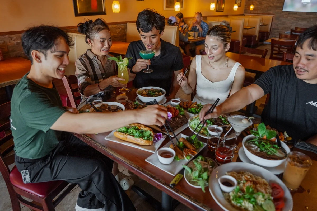 Group enjoying Vietnamese pho and cocktails at a restaurant