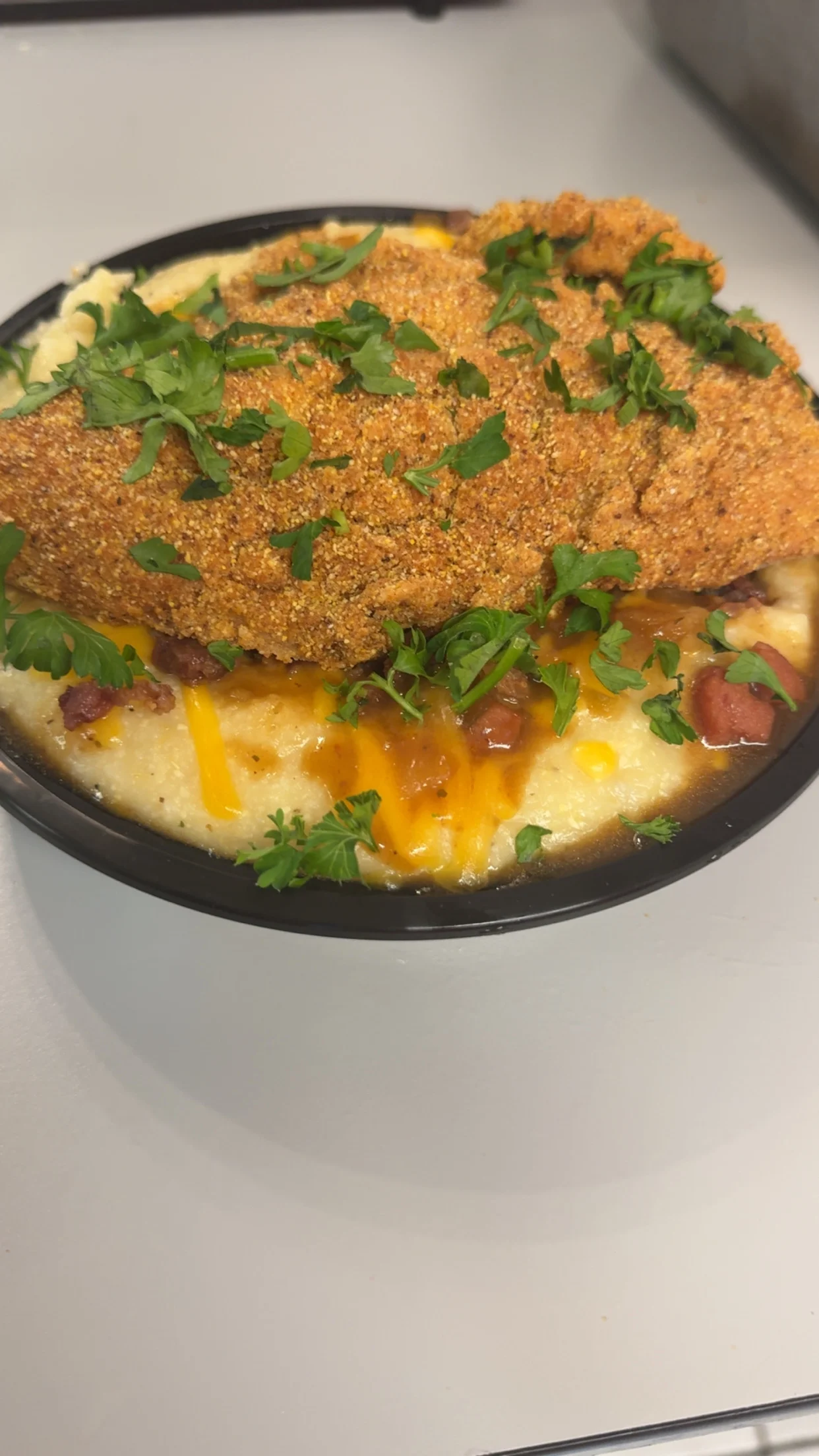 Fried chicken on creamy grits topped with cheese and herbs.