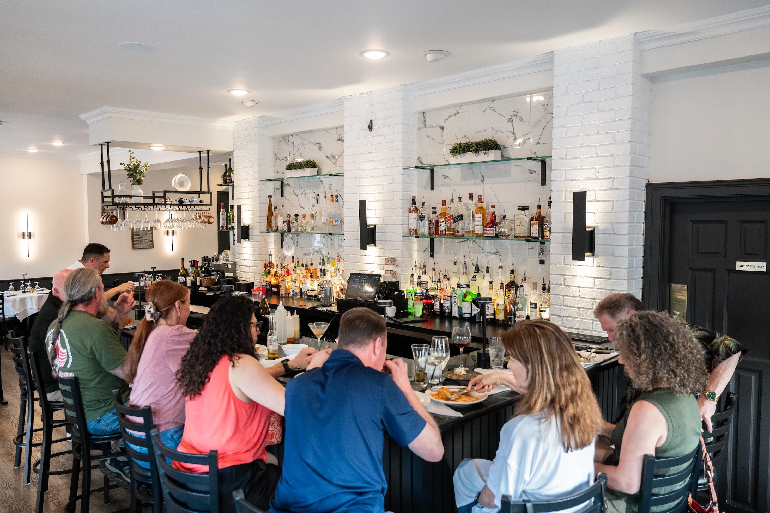 A vibrant bar scene with patrons enjoying drinks and meals at a stylish restaurant featuring a well-stocked bar