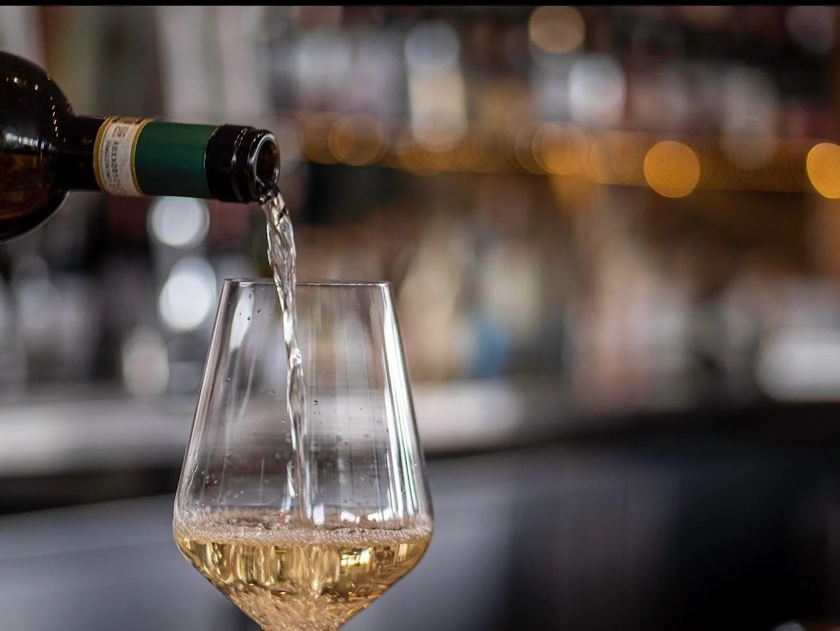 Pouring white wine into a glass at a bar