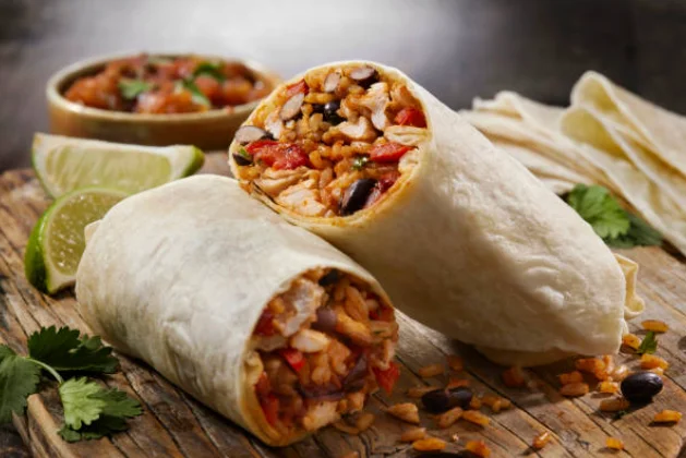 Delicious burrito filled with fresh ingredients on a wooden table.