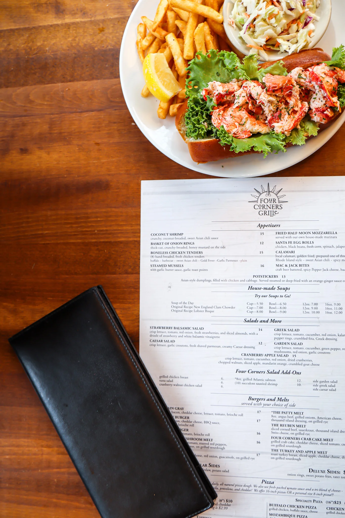 Lobster roll with fries and coleslaw in a coastal restaurant setting