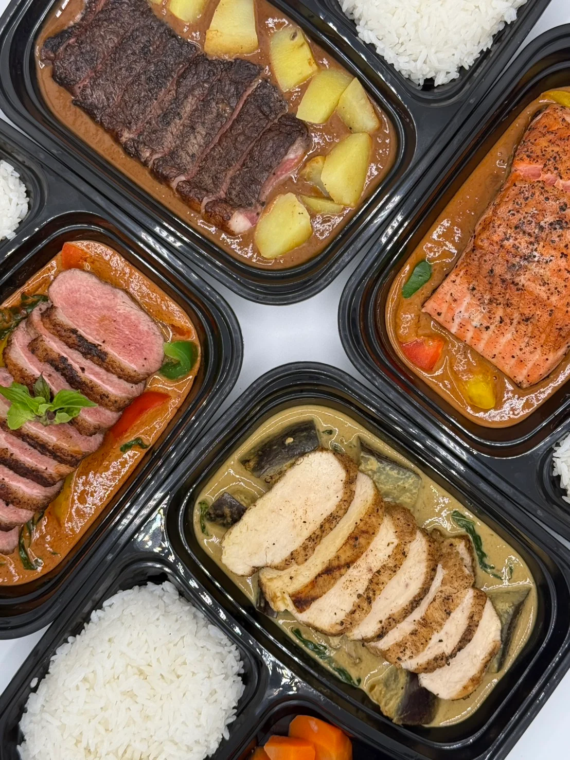 Assorted Asian-inspired meal boxes with grilled meats and rice